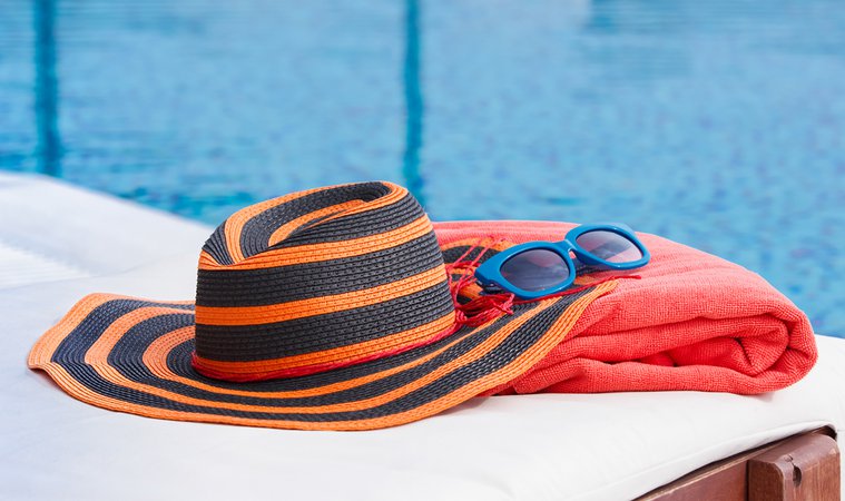 Sunbathing accessories on beach towel by a swimming pool