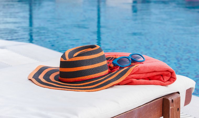 Sunbathing accessories on beach towel by a swimming pool